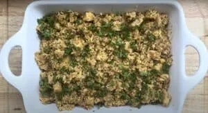 Delicious homemade stuffing with herbs in a white baking dish, perfect for Thanksgiving or holiday feasts.